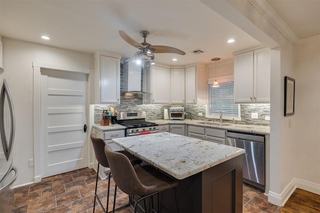 kitchen featuring wall chimney range hood, a sink, stainless steel appliances, baseboards, and visible vents