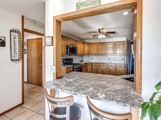 910860 S 3350th Rd, Wellston, OK 74881 - kitchen with a peninsula, brown cabinets, a kitchen bar, ceiling fan, and appliances with stainless steel finishes