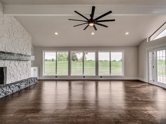 unfurnished living room featuring a ceiling fan, a stone fireplace, beam ceiling, and dark wood-type flooring