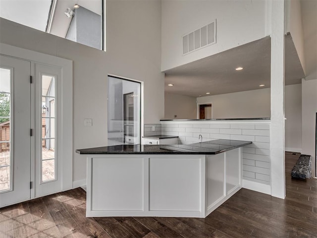 kitchen featuring visible vents, dark wood finished floors, a high ceiling, and white cabinetry