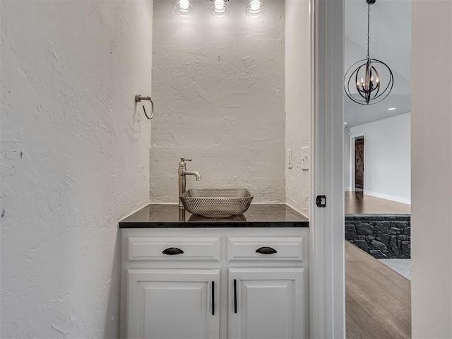 bar with hanging light fixtures, a textured wall, a chandelier, and a sink