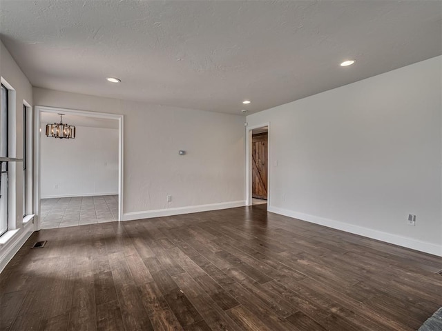 spare room with a textured ceiling, a chandelier, recessed lighting, baseboards, and wood finished floors