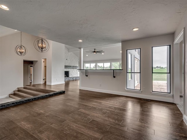 unfurnished living room with baseboards, dark wood-style floors, and ceiling fan with notable chandelier