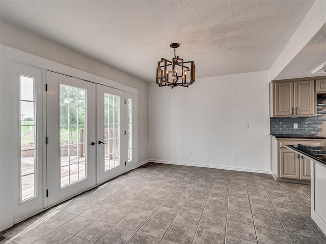kitchen featuring dark countertops, baseboards, tasteful backsplash, french doors, and a notable chandelier