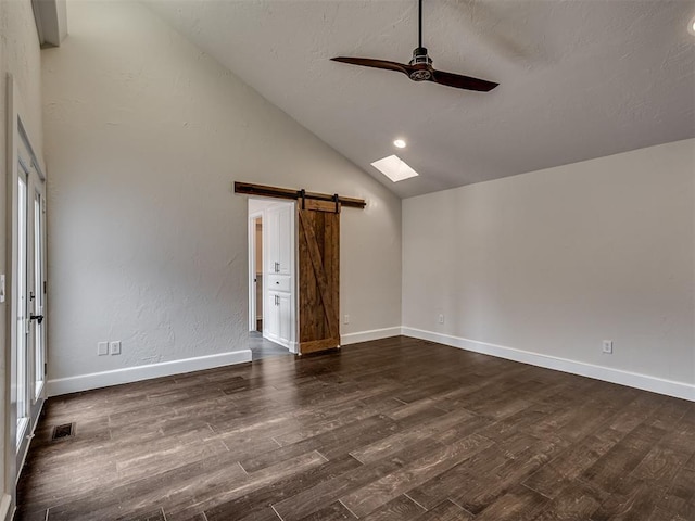spare room featuring a ceiling fan, dark wood-style flooring, visible vents, a barn door, and lofted ceiling