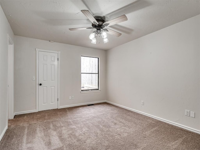carpeted empty room featuring visible vents, a textured ceiling, baseboards, and ceiling fan