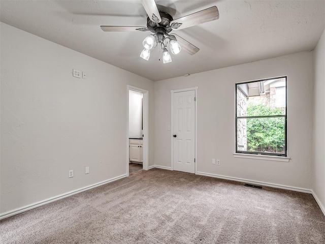 carpeted spare room with a ceiling fan, baseboards, and visible vents