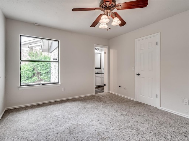 unfurnished bedroom featuring carpet floors, baseboards, ceiling fan, and ensuite bathroom