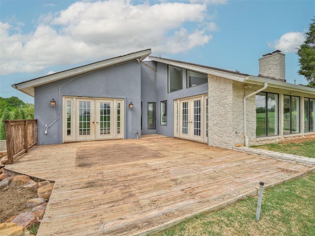 rear view of house with a deck, french doors, and a chimney