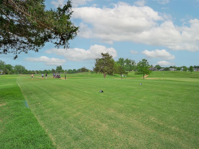 view of community featuring view of golf course and a yard