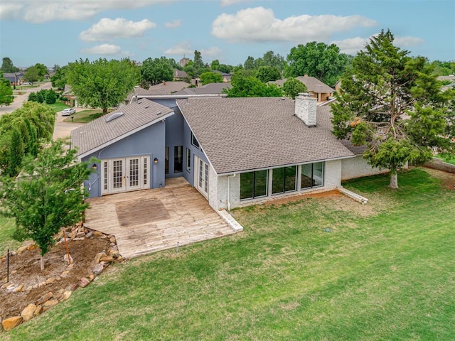 back of house featuring french doors, a shingled roof, a yard, and a chimney