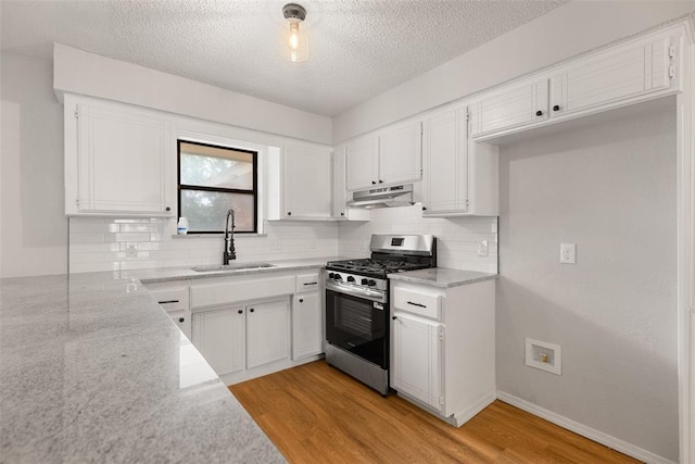 kitchen with a sink, stainless steel range with gas stovetop, light wood-style floors, and under cabinet range hood