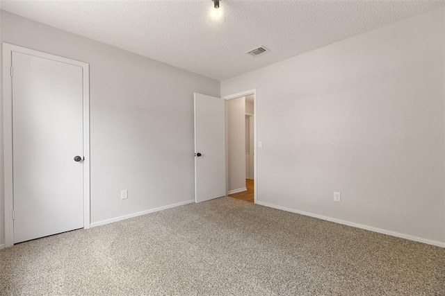 unfurnished bedroom with baseboards, carpet flooring, a textured ceiling, and visible vents