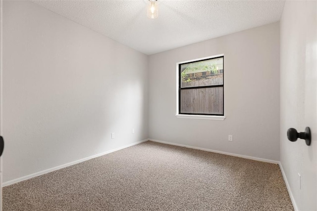 spare room with carpet floors, a textured ceiling, and baseboards