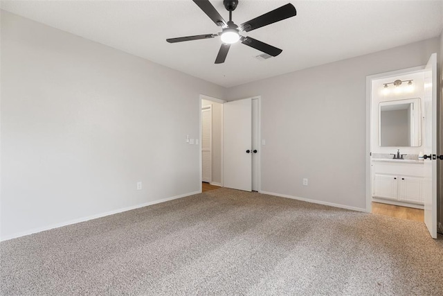 unfurnished bedroom featuring baseboards, a sink, ensuite bathroom, and light carpet