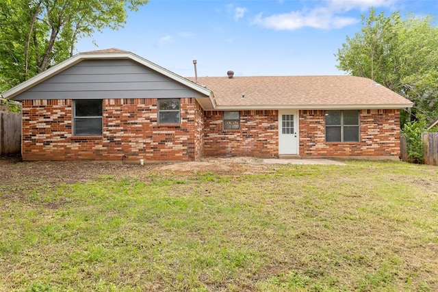 rear view of property with a lawn, fence, brick siding, and a patio