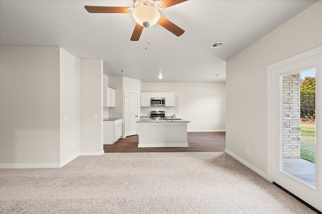 812 Stella Trl, Guthrie, OK 73044 - unfurnished living room featuring a ceiling fan, visible vents, a sink, baseboards, and dark carpet