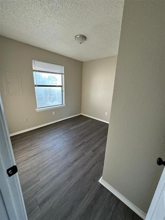 3509 N Nesbitt Ave, Oklahoma City, OK 73112 - unfurnished room with a textured ceiling, dark wood finished floors, and baseboards