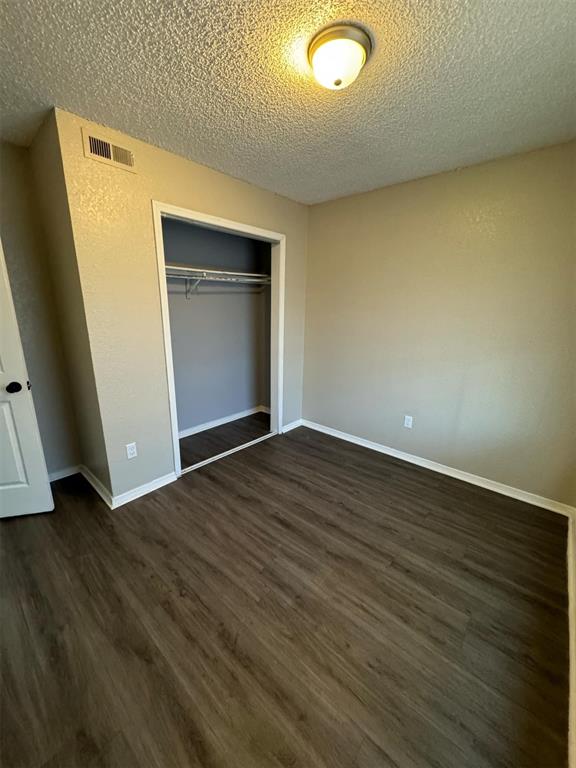 3509 N Nesbitt Ave, Oklahoma City, OK 73112 - unfurnished bedroom featuring a textured ceiling, dark wood-style flooring, a closet, and baseboards