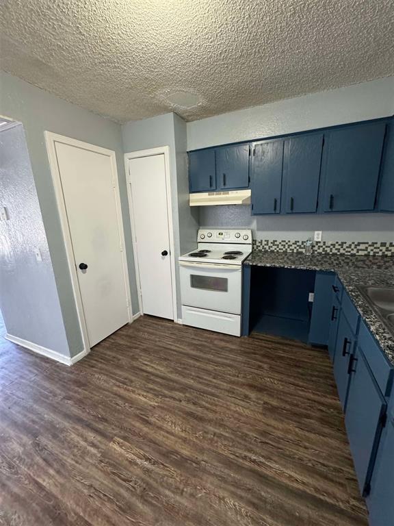 3509 N Nesbitt Ave, Oklahoma City, OK 73112 - kitchen with white range with electric stovetop, blue cabinets, under cabinet range hood, dark wood-type flooring, and a textured ceiling