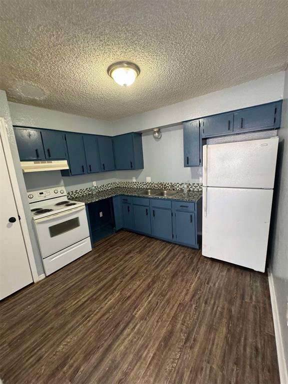 3509 N Nesbitt Ave, Oklahoma City, OK 73112 - kitchen featuring white appliances, blue cabinets, a textured ceiling, under cabinet range hood, and dark wood-style floors