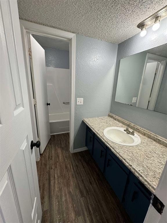 3509 N Nesbitt Ave, Oklahoma City, OK 73112 - full bath featuring a textured wall, wood finished floors, a textured ceiling, vanity, and a bathtub