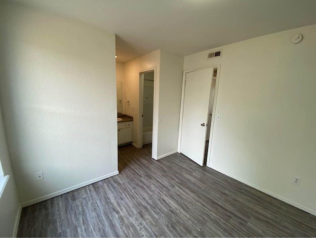 3509 N Nesbitt Ave, Oklahoma City, OK 73112 - unfurnished bedroom featuring dark wood-style flooring, baseboards, and connected bathroom
