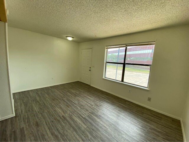 3509 N Nesbitt Ave, Oklahoma City, OK 73112 - unfurnished room featuring dark wood-style floors, a textured ceiling, and baseboards