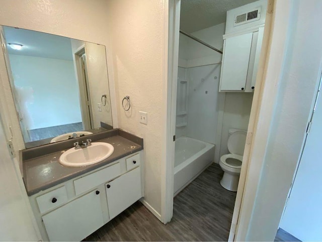 3509 N Nesbitt Ave, Oklahoma City, OK 73112 - full bathroom featuring wood finished floors, vanity, toilet, a textured wall, and washtub / shower combination