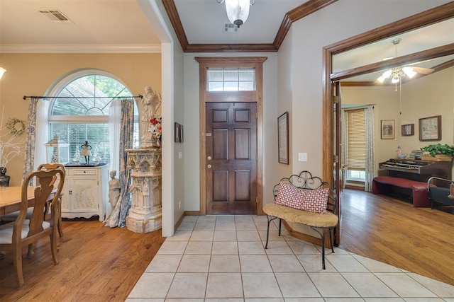 foyer entrance with crown molding, plenty of natural light, light wood finished floors, and visible vents