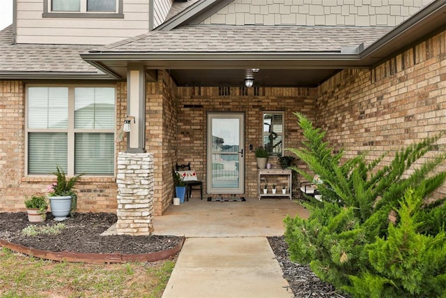 property entrance with a shingled roof and brick siding