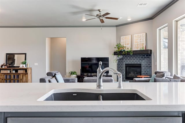 kitchen with open floor plan, plenty of natural light, a tiled fireplace, and ornamental molding