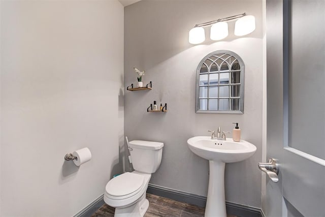 half bath featuring toilet, wood finished floors, and baseboards