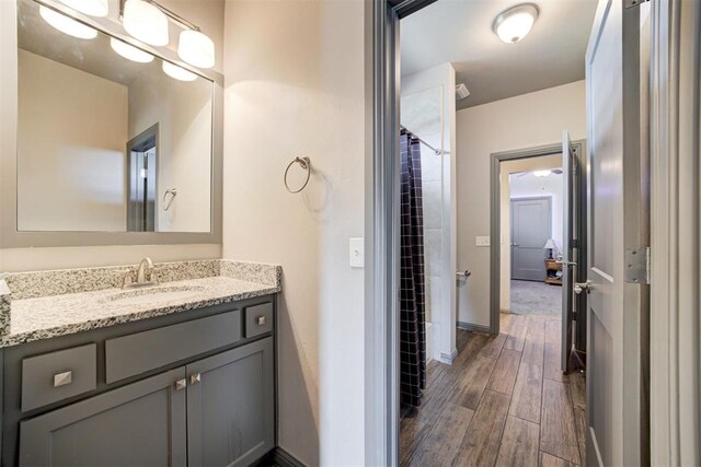 bathroom featuring wood finished floors, vanity, baseboards, and a shower