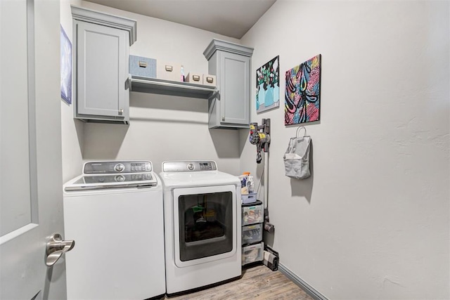 washroom featuring washing machine and dryer, cabinet space, light wood-style floors, and baseboards