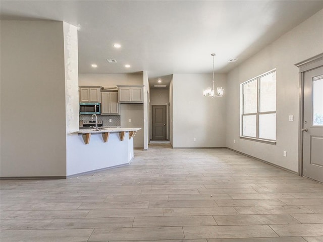 343787 E 870th Rd, Chandler, OK 74834 - kitchen featuring light wood-style floors, a breakfast bar area, light countertops, stainless steel microwave, and a notable chandelier