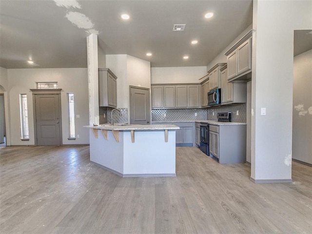 343787 E 870th Rd, Chandler, OK 74834 - kitchen with electric range oven, a peninsula, stainless steel microwave, a kitchen bar, and visible vents