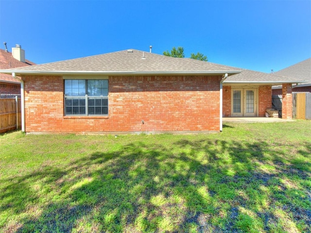 rear view of house featuring fence, a yard, and brick siding