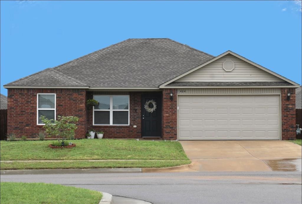 ranch-style home with a front yard, roof with shingles, brick siding, concrete driveway, and an attached garage