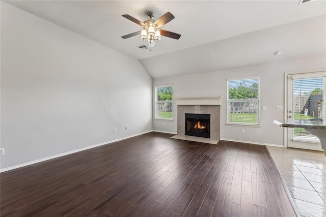 unfurnished living room featuring visible vents, a tiled fireplace, a wealth of natural light, and hardwood / wood-style flooring