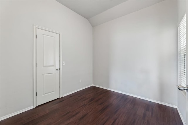 empty room featuring baseboards, dark wood-style flooring, and vaulted ceiling