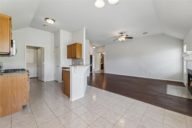 kitchen with stainless steel microwave, a peninsula, open floor plan, and lofted ceiling
