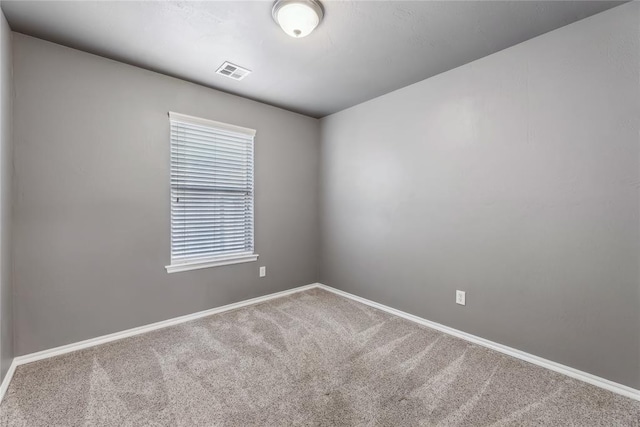 spare room featuring carpet flooring, baseboards, and visible vents
