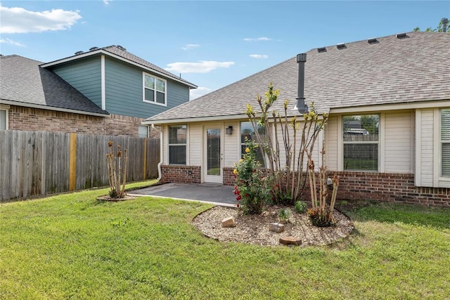 rear view of house featuring a lawn, brick siding, fence, and a patio area