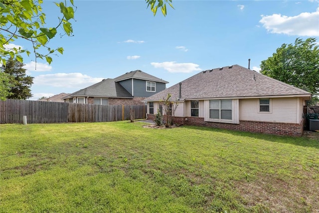 back of property with a lawn, brick siding, and a fenced backyard