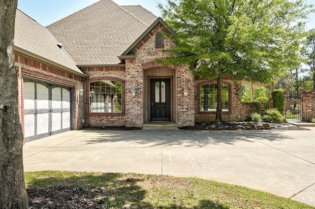 view of front facade with a garage, fence, roof with shingles, brick siding, and concrete driveway