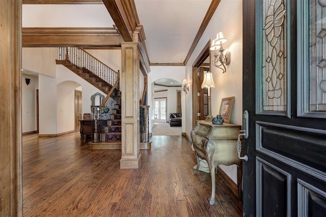 entrance foyer with crown molding, arched walkways, stairs, baseboards, and wood finished floors