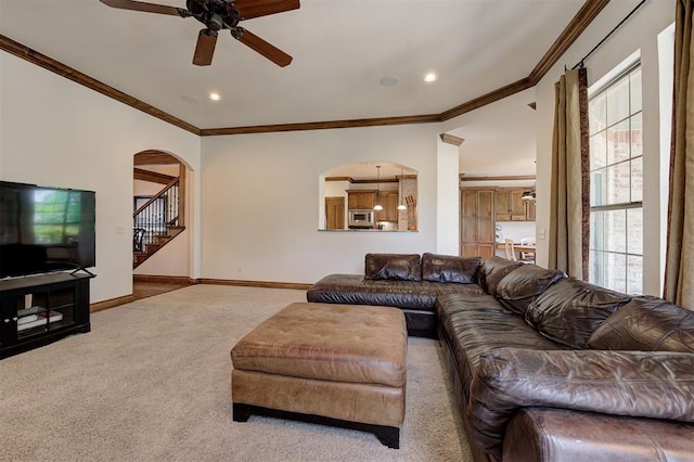 living area featuring crown molding, ceiling fan, arched walkways, carpet, and stairway