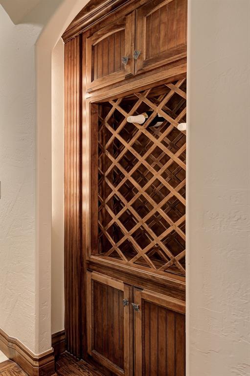 wine area with arched walkways, baseboards, dark wood-style floors, and a textured wall