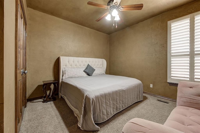 bedroom featuring ceiling fan, carpet flooring, a textured wall, and visible vents